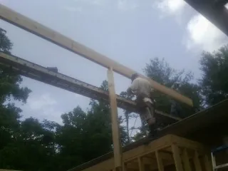 Carpenter setting a ridge beam over a new addition frame — Ice Dam Removal by Roofing Brothers in Piney Point