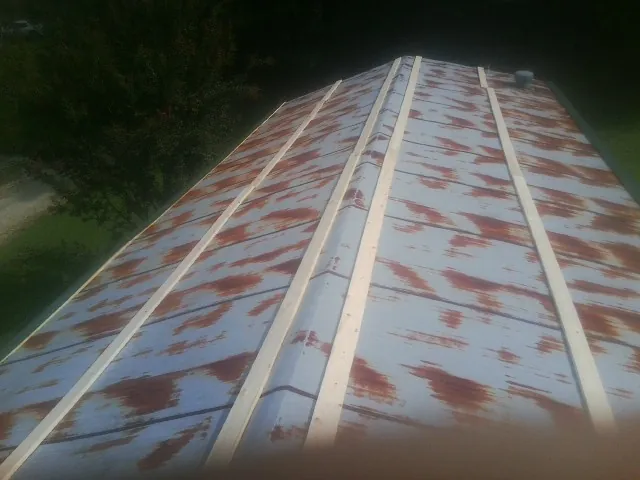 Rusted metal roof panels with new wood purlins before replacement — Storm Damage Roof Repair in Piney Point by Roofing Brothers