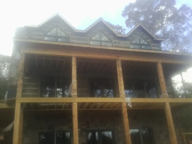 Dormers and porch framing on a large log home under construction — Roof Coating work by our crew in Piney Point