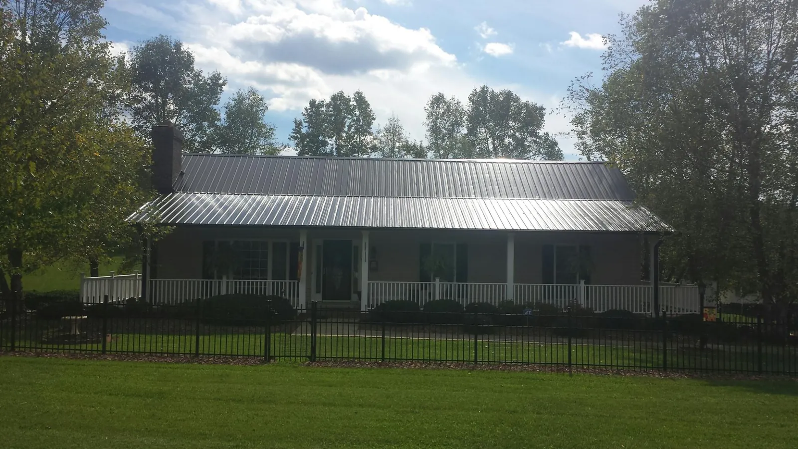Gray metal roof on a brick ranch with a full width front porch — Gutter Guard Installation work by our crew in Piney Point