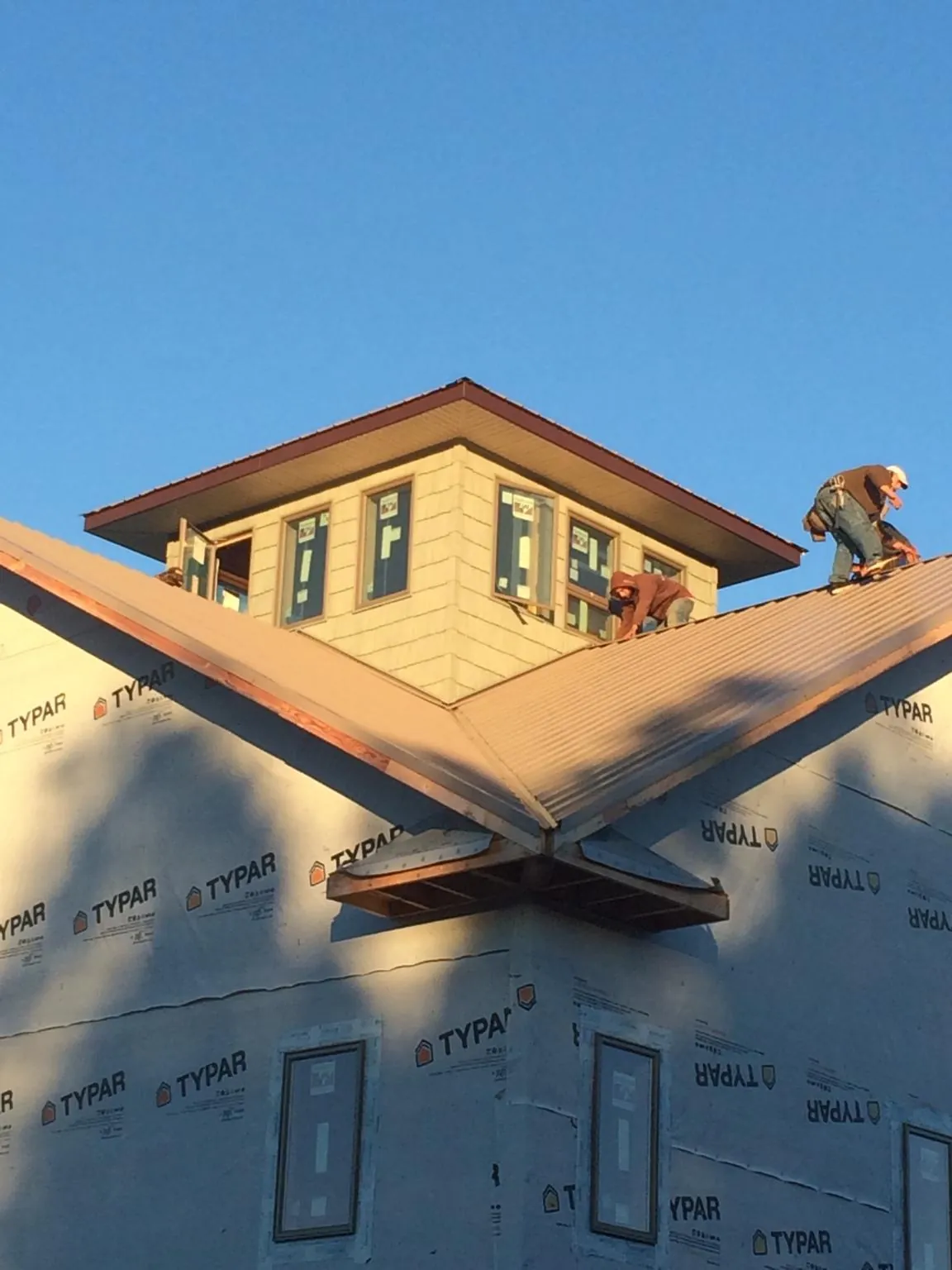 Roofers working around a rooftop cupola on a new metal roof at sunset — Roof Waterproofing in Piney Point by Roofing Brothers